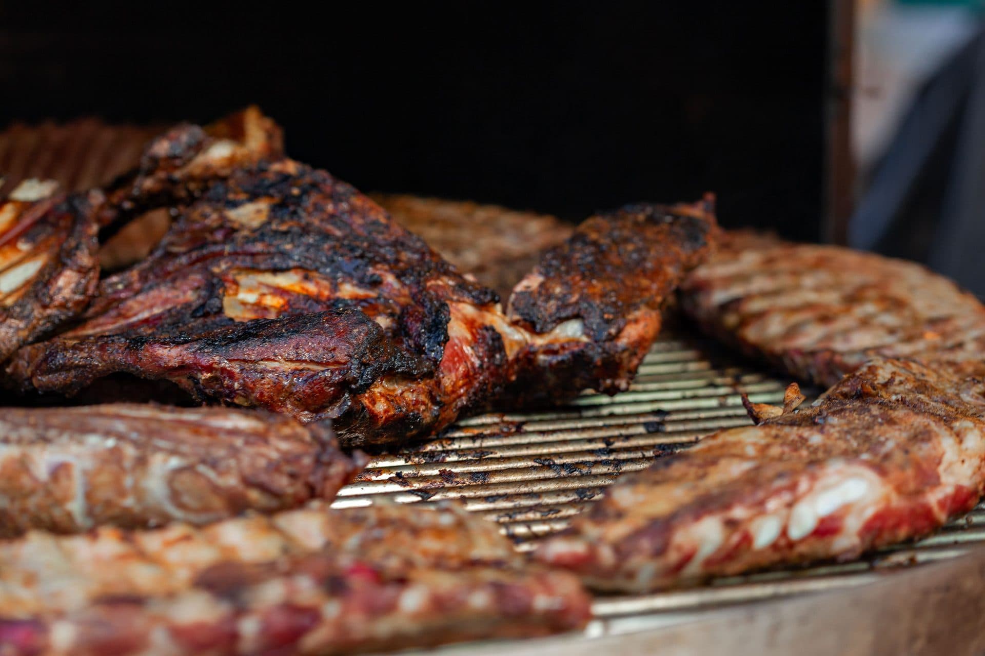 Verschiedene Fleischstücke nebeneinander auf dem Grillrost, kräftig gebräunt