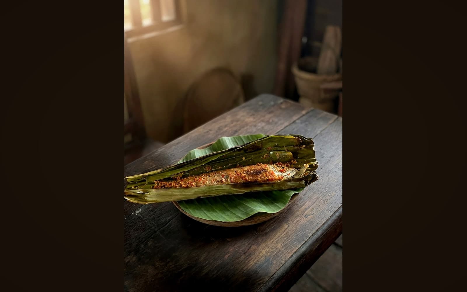 Ganzer gegrillter Fisch im gefalteten Bananenblatt