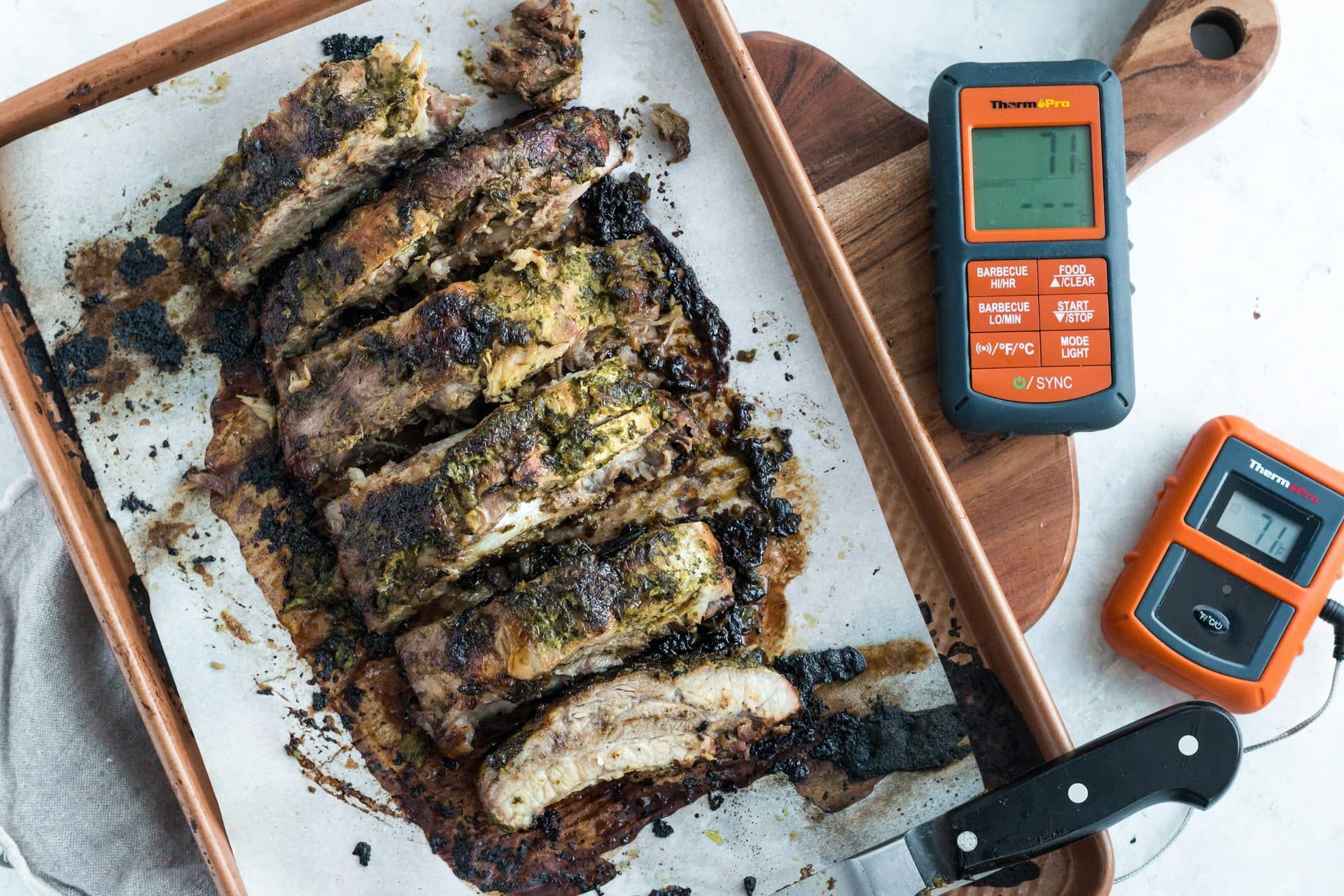 Gegrilltes Fleisch auf einem Brett, daneben zwei digitale Fleischthermometer